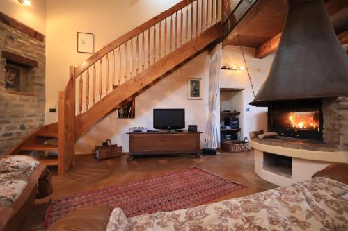a living room with a fireplace and a staircase at Splendida casa in sasso in borgo in Canossa