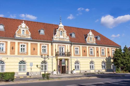 un grand bâtiment en briques avec un toit rouge dans l'établissement Hotel Kristály Imperial, à Tata
