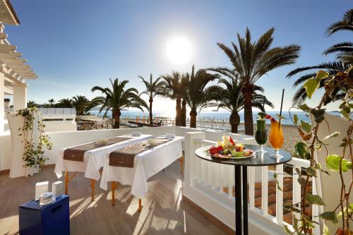 a table on the balcony of a villa with the beach at Ushuaïa Ibiza Beach Hotel - Adults Only - Club Entrance Included in Playa d'en Bossa