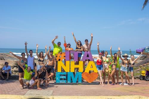 a group of people posing in front of the beach at Namoa Pollastrini in Itanhaém