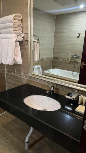 a bathroom with a sink and a mirror and a tub at Mountain View Residence Hotel in Almaty