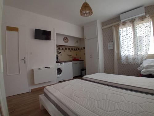 une chambre blanche avec un lit et une cuisine dans l'établissement Centre ville d'Amelie les bains, à Amélie-les-Bains-Palalda