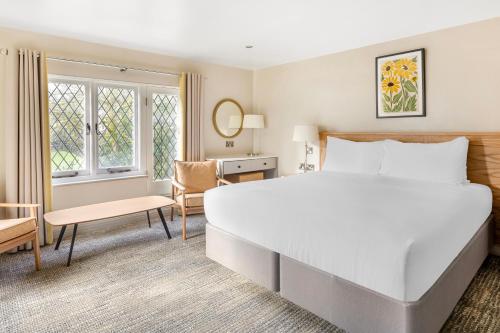 a bedroom with a large white bed and a desk at Woodford Bridge Country Club in Milton Damerel