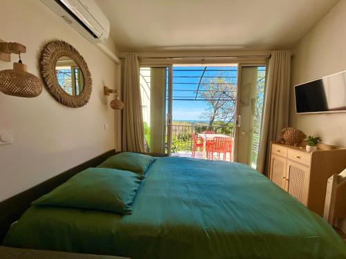 - une chambre avec un grand lit vert et un balcon dans l'établissement Les Restanques IRIS 2124, à Grimaud