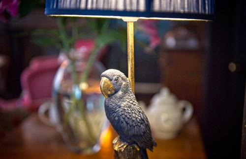 a bird is sitting on a lamp on a table at The Old Vicarage Hotel & Restaurant in Bridgwater
