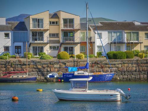 a boat is docked in the water in front of houses at 66D South Snowdon Wharf in Porthmadog
