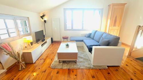 a living room with a blue couch and a table at f2 VUE INCROYABLe sur lac avec jardin avec balnéo et 400m centre in Gérardmer