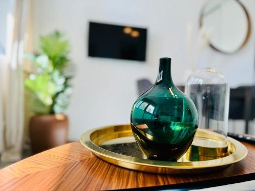 un vase de verre vert sur une plaque d'or sur une table dans l'établissement Suite Bayah - Check in h24 - Wifi, à Lyon