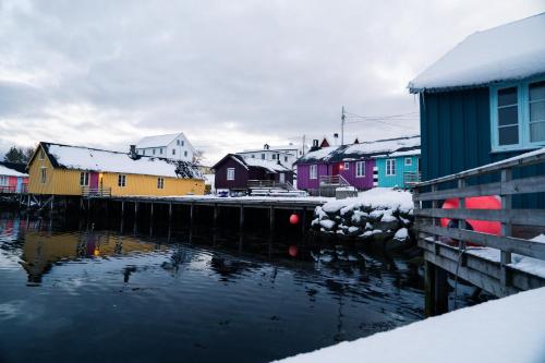 a small town with houses and a body of water at Kræmmervika Rorbuer - Rustic Cabins & Hostel in Lofoten in Ballstad