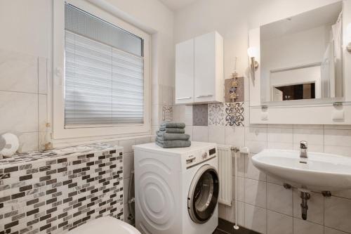a white bathroom with a washing machine and a sink at Ferienhaus Pfanne in Hennstedt