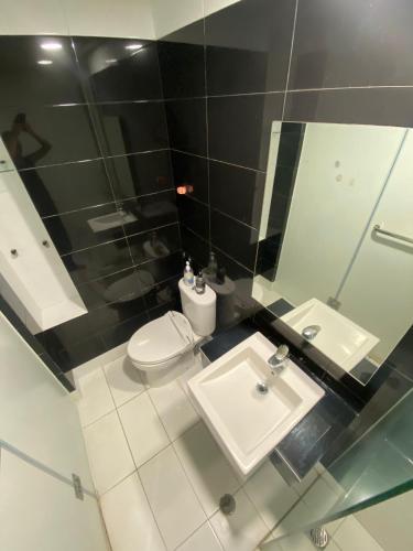 a bathroom with a sink and a toilet and a mirror at The Square - King Suite - Apartemen Service - 2Person - NetFlix Wifi - Near Petra Campus in Surabaya