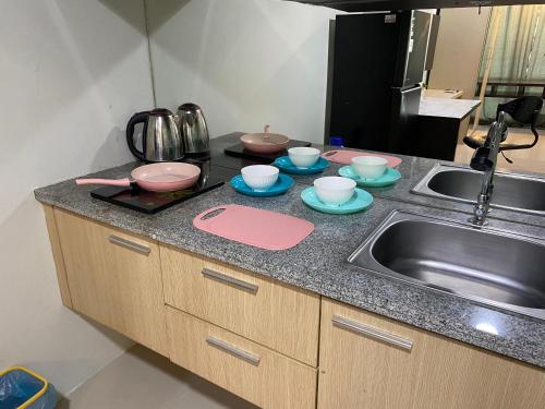 a kitchen counter with a sink and bowls and dishes at The Square - King Suite - Apartemen Service - 2Person - NetFlix Wifi - Near Petra Campus in Surabaya