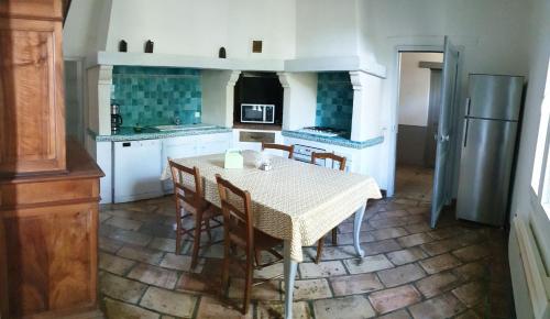 une cuisine avec une table avec des chaises et un réfrigérateur dans l'établissement la régie, à Arles