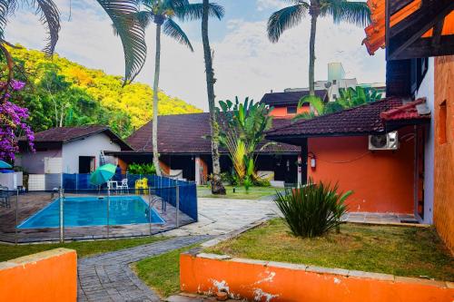 a house with a swimming pool and palm trees at Chalés Suítes Ubatuba Paradise Toninhas in Ubatuba