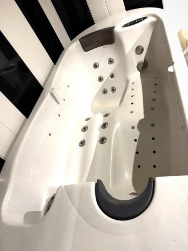 une baignoire blanche avec un mur noir et blanc dans l'établissement La Maison Évasion, à Causses-et-Veyran