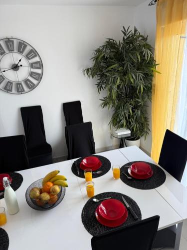 - une table blanche avec des assiettes rouges et des fruits dans l'établissement La Maison Évasion, à Causses-et-Veyran