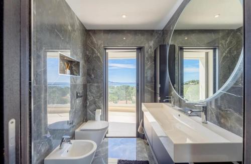 une salle de bain avec deux lavabos et un grand miroir dans l'établissement Vue mer à couper le souffle - Villa d'architecte, à Bandol