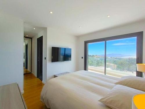 une chambre avec un grand lit avec une grande fenêtre dans l'établissement Vue mer à couper le souffle - Villa d'architecte, à Bandol