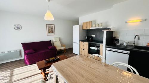 Il comprend une cuisine et un salon avec un canapé violet. dans l'établissement T2 de la Garenne, calme et forêt, à Saint-Jean-de-Monts