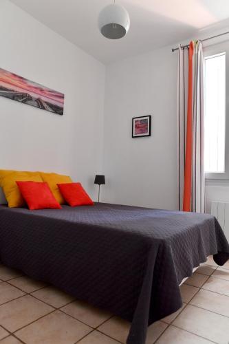 - une chambre avec un lit doté d'oreillers rouges et jaunes dans l'établissement Le Miradou, à Arles