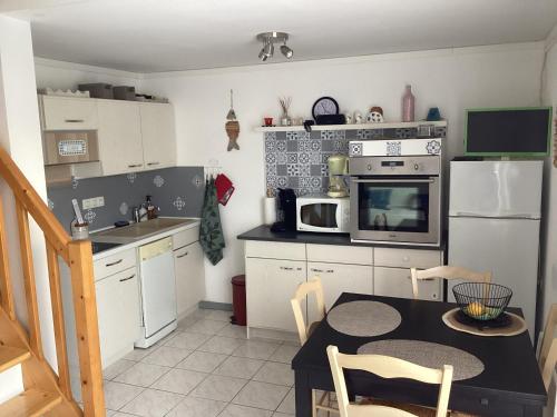 une petite cuisine avec une table et un micro-ondes dans l'établissement MAISON Estivale Royan Vaux sur Mer, à Vaux-sur-Mer