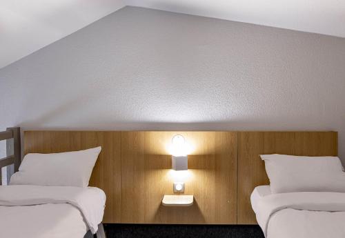 two beds in a room with two lights on the wall at B&B HOTEL Bordeaux Mérignac Hôtel de Ville in Mérignac
