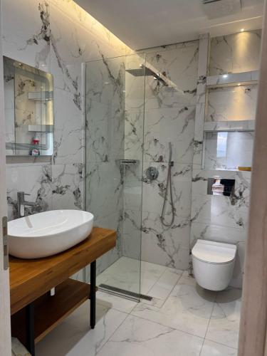 a bathroom with a sink and a toilet and a shower at Dania Sea View Apartments in Sarandë