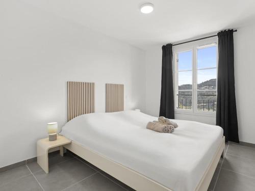 une chambre blanche avec un grand lit et une fenêtre dans l'établissement 70m2, piscine , 2 chambres, à La Garde-Freinet
