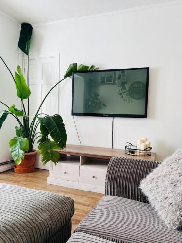 a living room with a couch and a tv on a wall at The Annexe at Tenniside in Perranporth