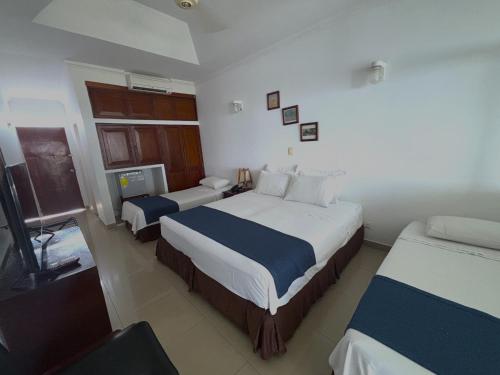 a hotel room with two beds and a television at Hotel Los Puentes Comfacundi in Girardot