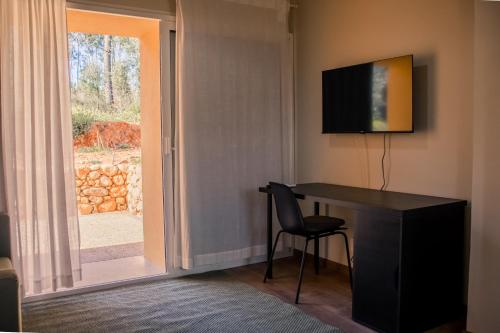 a room with a desk with a television and a window at Quinta-lina de serpins in Serpins