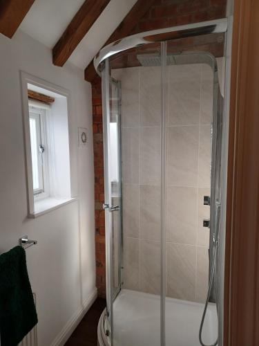 a shower with a glass door in a bathroom at The Studio Loft - A cosy town centre apartment in Tewkesbury