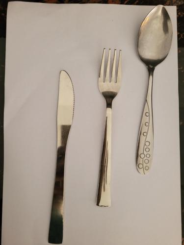 two forks and a spoon on a white table at Pearl House Homestay in Dickwella