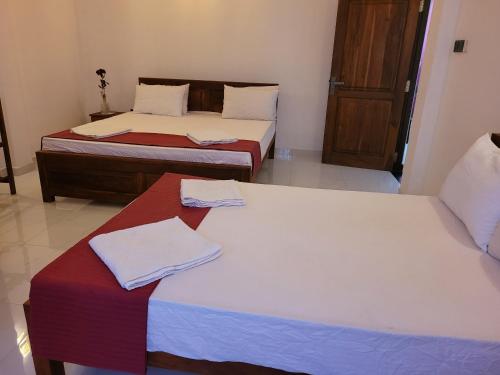 two beds in a room with towels on them at Pearl House Homestay in Dickwella