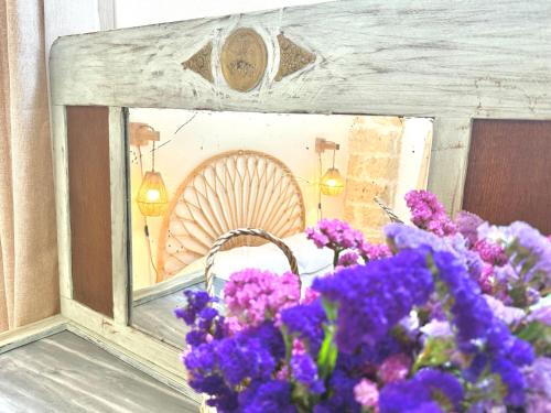 a mirror with purple flowers in front of a table at Casa Pesimena in Galatone