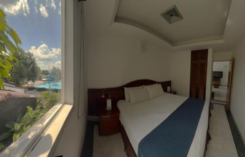 a bedroom with a bed and a large window at Hotel Los Puentes Comfacundi in Girardot