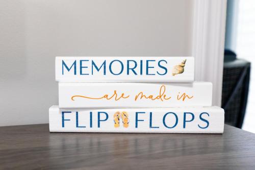a stack of books with the words memories are made in flip flops at At the Beach - Old Homestead Beach House in Huron