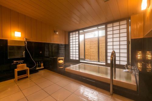 ein großes Bad mit einer Badewanne und einem Fenster in der Unterkunft Chousenkaku Kameya in Shimo-suwa