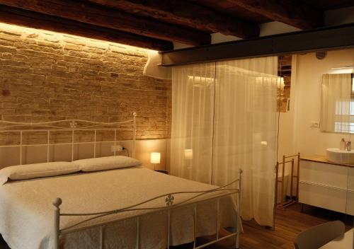a bedroom with a bed and a brick wall at Onda Marina B&B Superior in Marano Lagunare