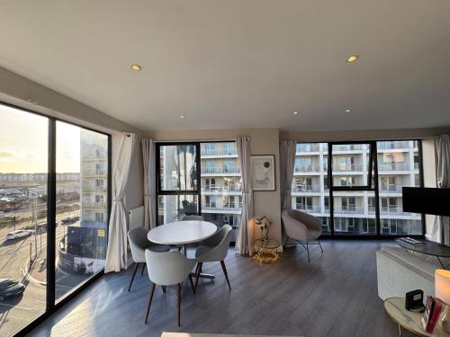 a living room with a table and chairs and windows at Penthouse - Harbour Views in Poole