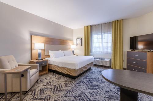 a hotel room with a bed and a couch and a table at Candlewood Suites San Marcos by IHG in San Marcos