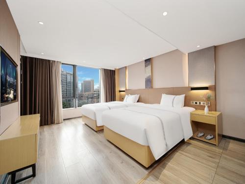 a hotel room with two beds and a large window at Yishang Hotel - Guangzhou Railway Station Yuexiu Park Subway Station in Guangzhou