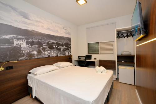 a bedroom with a large white bed and a desk at North Savassi in Belo Horizonte