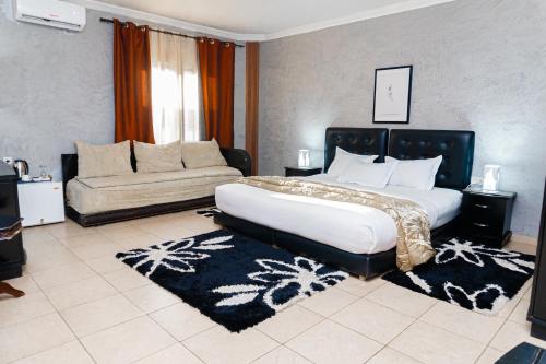 a bedroom with a large bed and a couch at Hotel de Fez in Pointe-Noire