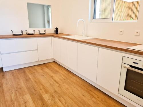 a kitchen with white cabinets and a wooden floor at Villa Californienne au calme in Berre-les Alpes