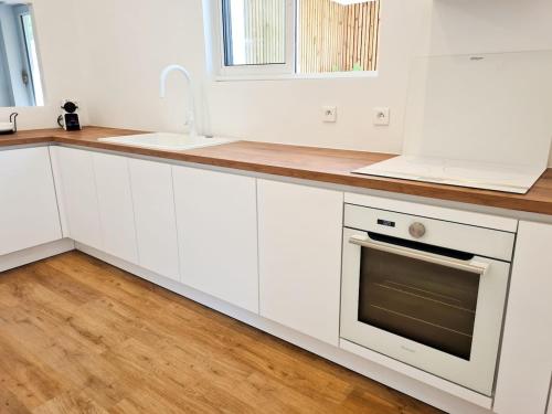 a white kitchen with white cabinets and a sink at Villa Californienne au calme in Berre-les Alpes
