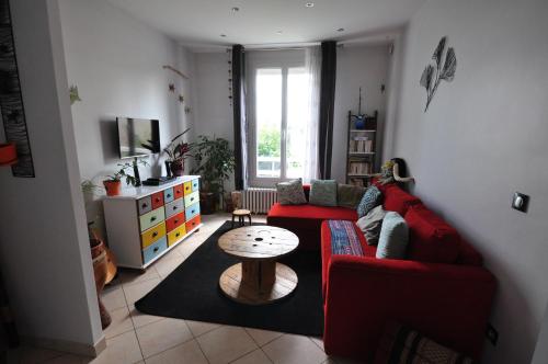 a living room with a red couch and a table at Maison Jardin Proche Paris in Sainte-Geneviève-des-Bois