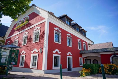 ein rot-weißes Gebäude mit einem Baum in der Unterkunft Schärhaus in Windischgarsten