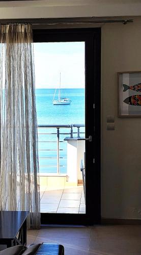 a door to a balcony with a boat in the ocean at Sea and Sun Luxury apartment in Neoi Epivates