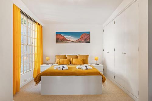 a white bedroom with a large bed with orange sheets at Quinta Paraiso in Funchal